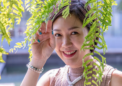 Portrait of smiling young woman holding plant