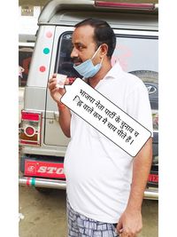 Midsection of man holding text while standing on bus