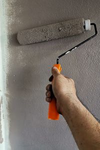 Close-up of man holding stick against orange wall