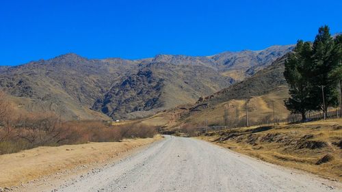 Road amidst mountains against clear blue sky