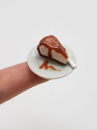 Close-up of hand holding ice cream over white background