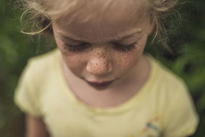 High angle close-up of girl with freckles standing in forest