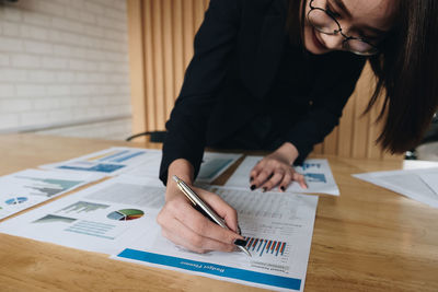 Midsection of woman reading book on table