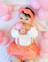 Portrait of cute girl with balloons lying down on bed