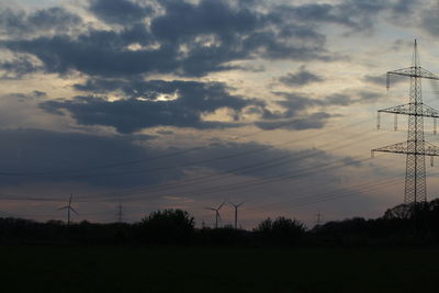 Silhouette of electricity pylon against sunset sky