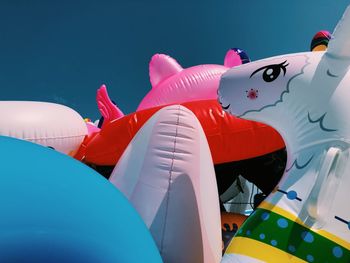 Close-up of various inflatables beach toys on beach against clear summer sky.