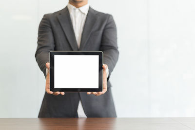 Midsection of man holding mobile phone while standing on table