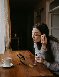Side view of young woman using mobile phone at home