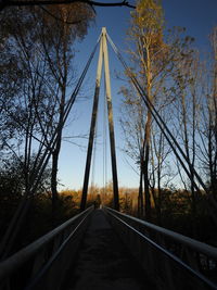 Footbridge amidst trees against sky