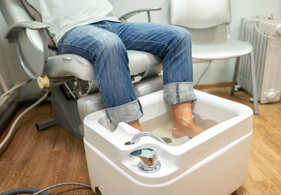 Low section of woman sitting in bathroom