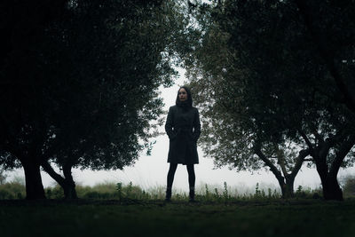 Full length of woman standing on field in forest