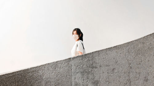 Low angle view of woman standing against wall