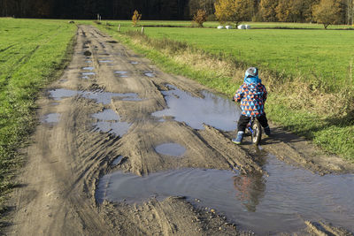 People riding bicycle on road amidst field