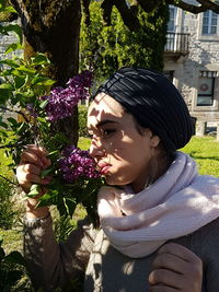 Close-up of woman smelling purple flowering plants