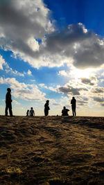 Silhouette people on field against sky during sunset