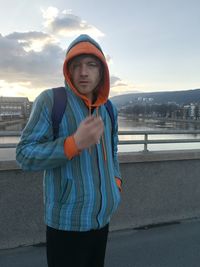 Portrait of man standing in city against sky during sunset