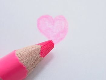 Close-up of pink heart shape on table against white background