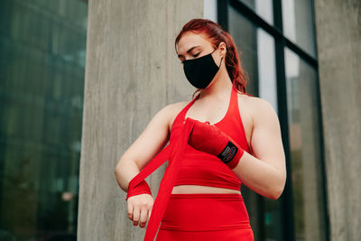 Young woman standing against wall