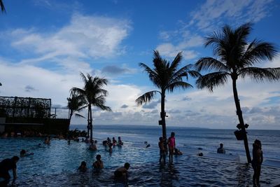 Tourists on beach against cloudy sky