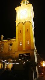 Low angle view of illuminated clock tower at night