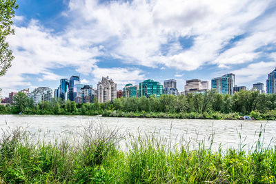 Scenic view of river by buildings against sky