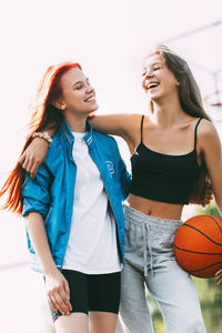 Two funny girls with a basketball hug each other after a game or workout. the concept of sports 