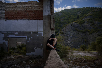 Woman with umbrella on street amidst trees against sky