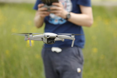 Midsection of person holding camera while standing on field