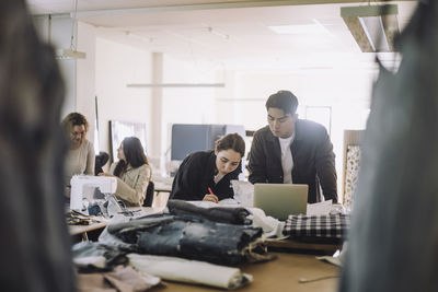 Multiracial male and female design professionals working on laptop at workshop