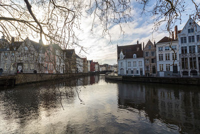 Canal by buildings in city against sky