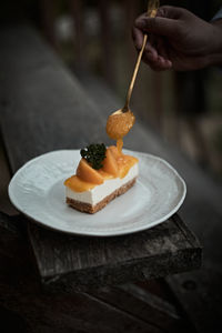 Close-up of hand holding cake on table