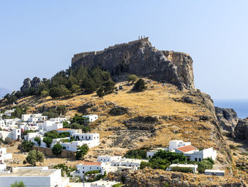 Residential buildings by mountain against clear sky