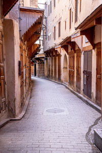 Footpath or narrow alley amidst residential structure with closed doors