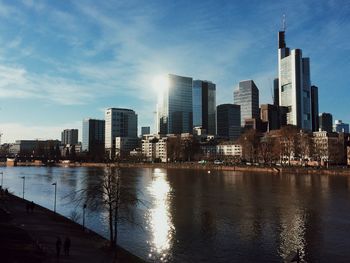 River by modern buildings against sky in city