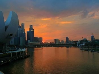 River by buildings against sky during sunset