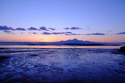 Scenic view of beach against sky at sunset