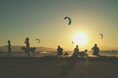 Silhouette people on beach against clear sky during sunset