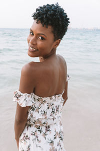 Portrait of smiling woman looking away while standing on beach