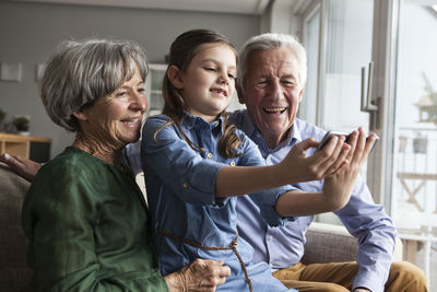 Little girl taking selfie with her grandparents at home