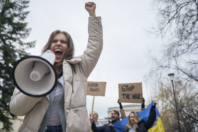 Low angle view of young woman standing against sky