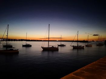 Sailboats moored in marina at sunset