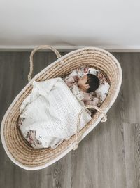 Directly above shot of baby sleeping in basket at floor