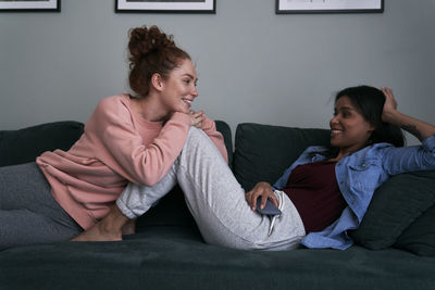 Happy friends talking while sitting on sofa