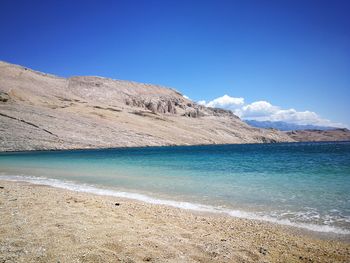 Scenic view of sea and mountains against blue sky