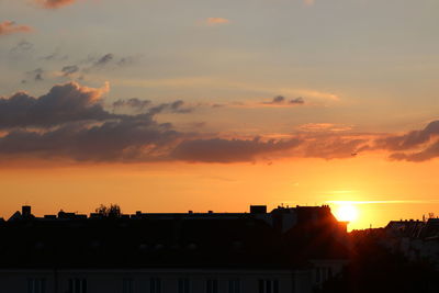 Silhouette buildings against dramatic sky during sunset