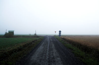 Rear view of man on road amidst field against fog