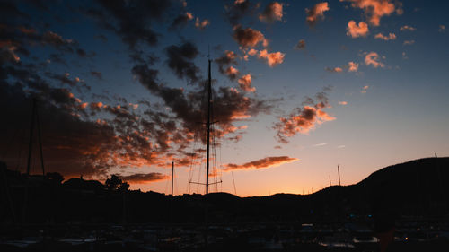 Silhouette city against dramatic sky during sunset