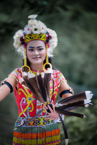 Portrait of smiling young woman wearing traditional clothing standing against sky