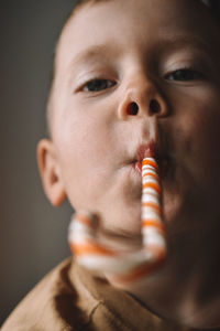 Close-up portrait of cute boy eating candy cane