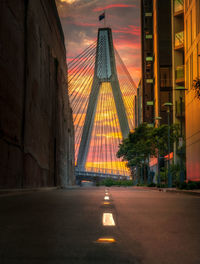 Illuminated bridge in city against sky during sunset